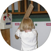 Young child hitting the wall with a board.