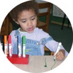 Preschool girl drawing with markers.