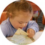 Young girl with head down turning the pages of a book.