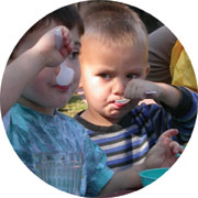 Two toddler boys eating with a spoon .