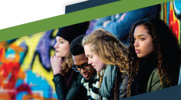 Four young adults sitting ouside in front of a colorful mural.
