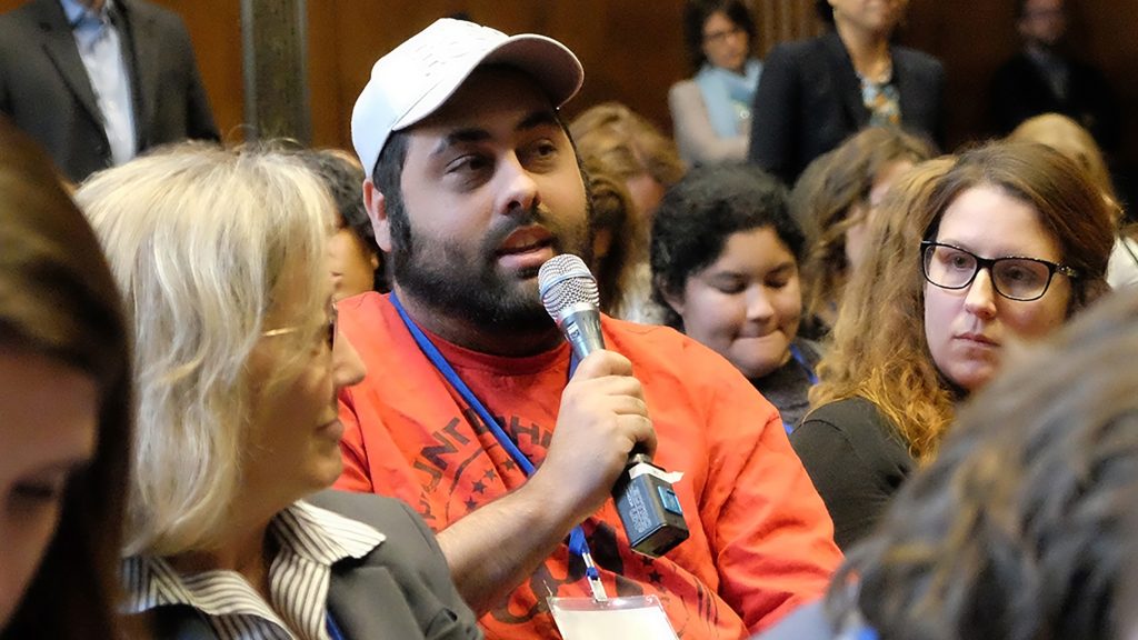 Kily Pelletier speaking into a microphone to ask a question from the audience at the AUCD Plenary in 2018.