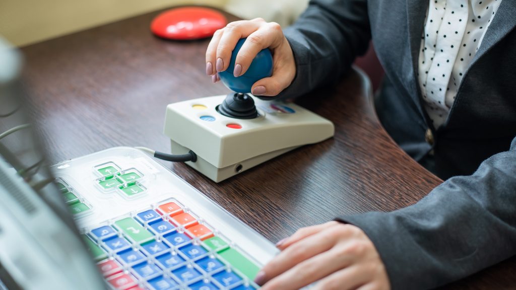 A person using a joystick mouse to access their laptop.