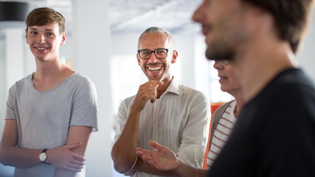 Three men standing around enjoying a discussion.
