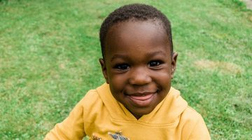 Young Black boy sitting in the grass..
